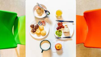 Una mesa con alimentos para el desayuno, como cereales, fruta y bollería, junto con una taza y un vaso de jugo.