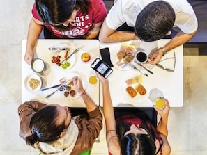 Un groupe de personnes est assis autour d’une table, devant divers plats et boissons.