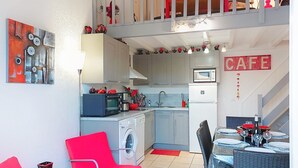 Angolo cottura compatto con forno a microonde, tostapane e lavello. C'è una zona pranzo con tavolo e sedie.