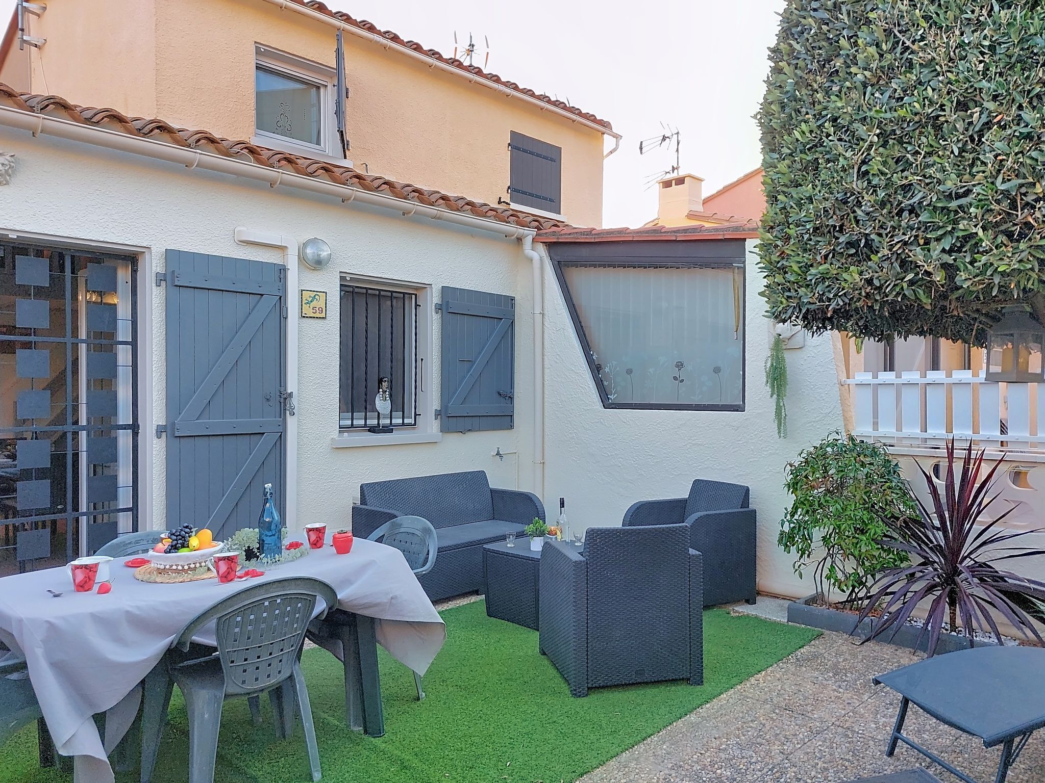 A patio with outdoor furniture, a table set for a meal, and a small garden area.