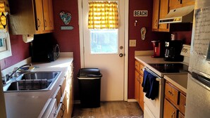 Una cocina compacta con armarios de madera, un lavamanos, un microondas y un refrigerador.