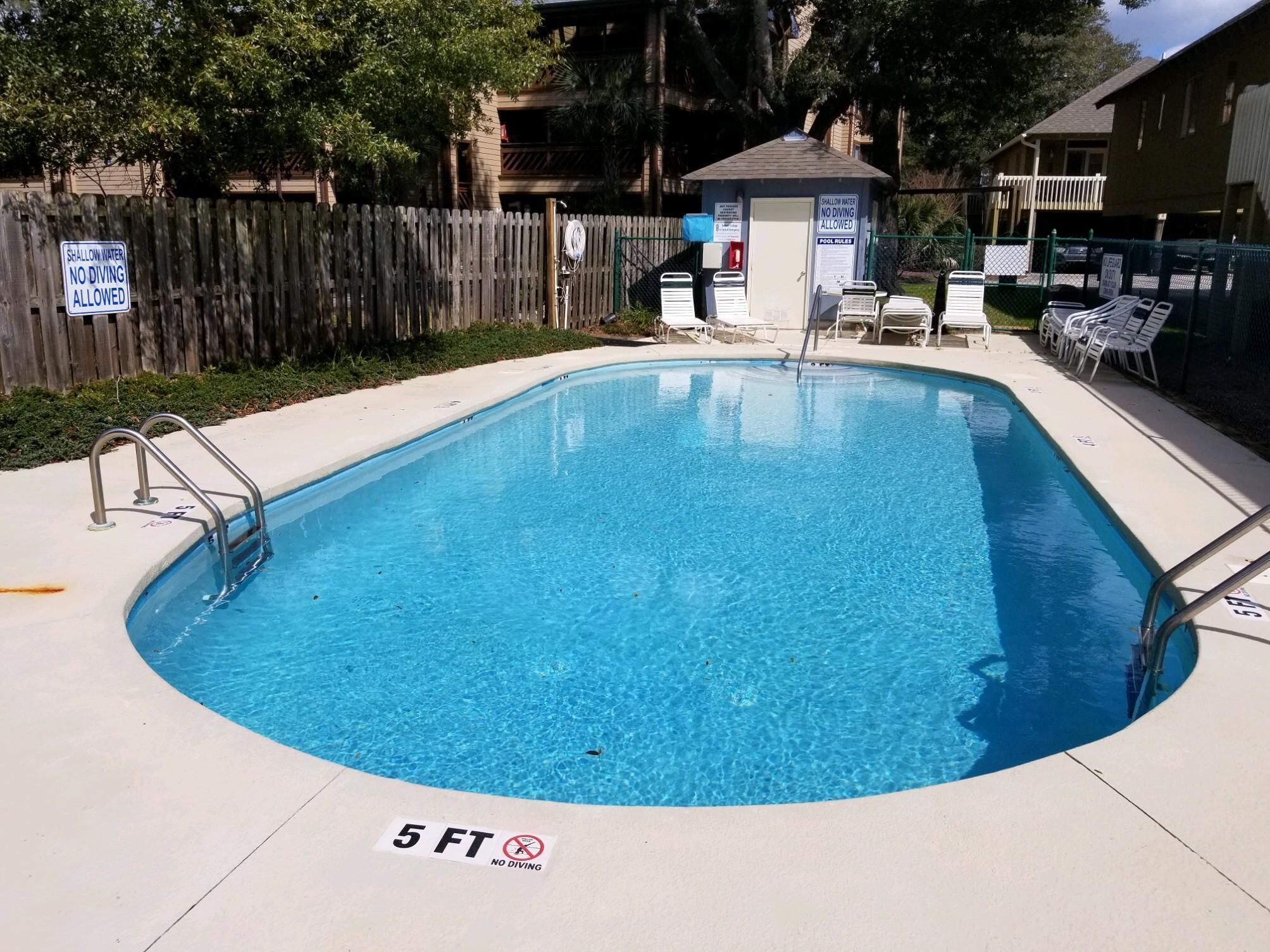 A rectangular pool with a 5 ft no-diving zone, surrounded by a wooden fence and lounge chairs.