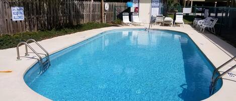 A rectangular pool with a 5 ft no-diving zone, surrounded by a wooden fence and lounge chairs.