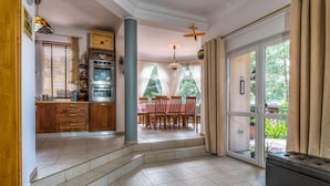 A spacious kitchen with a dining area, large windows, and a view of greenery. - Willa Wiktoria (Wladyslawowo)