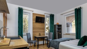 A hotel room with a bed, a desk with a chair, a television mounted on the wall, and a wardrobe. - Willa Wiktoria (Wladyslawowo)