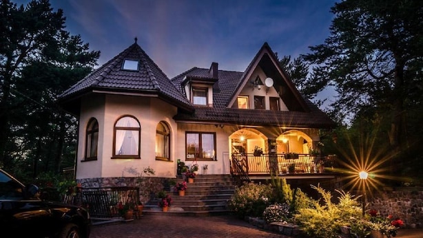 A two-story house with a brick driveway, a front porch with a railing, and a car parked on the left. - Willa Wiktoria (Wladyslawowo)