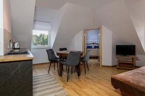 A compact room with a kitchenette, a dining area with chairs, a TV, and a bed. - Willa Wiktoria (Wladyslawowo)