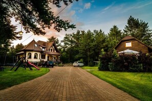 A residential property with a paved driveway, a play area with a slide, and a large house with a prominent chimney. - Willa Wiktoria (Wladyslawowo)