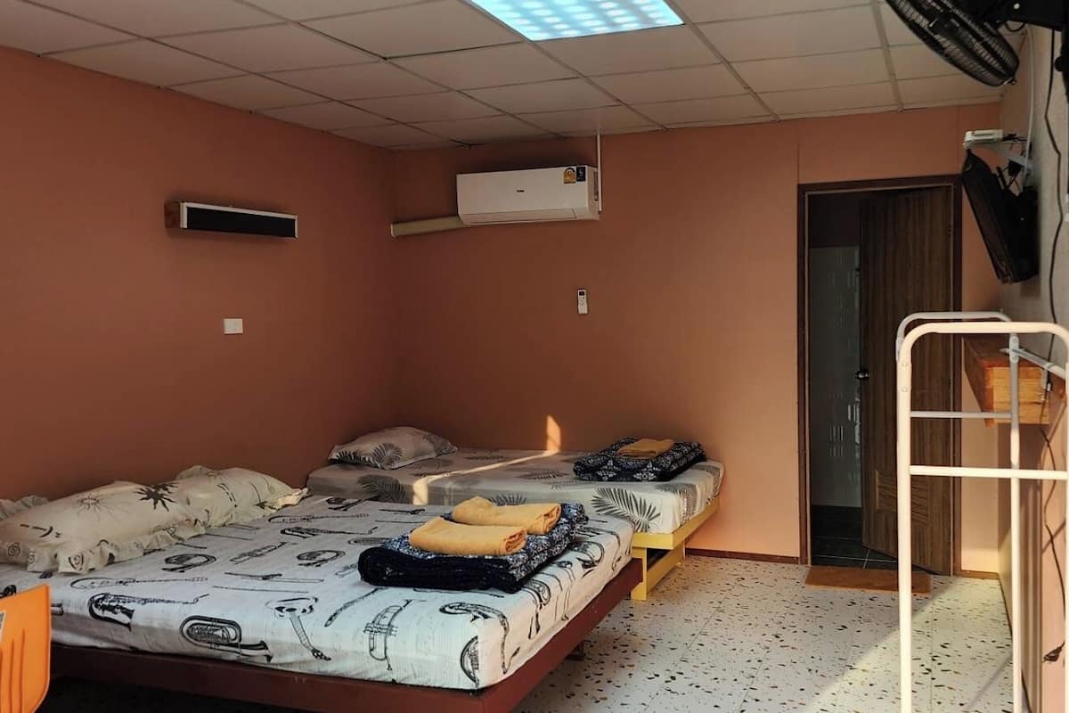 Une chambre de dortoir avec deux lits, un bureau, un climatiseur et une échelle.