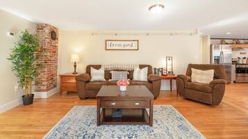 A living room with a brown sofa, a coffee table, and a brick accent wall.