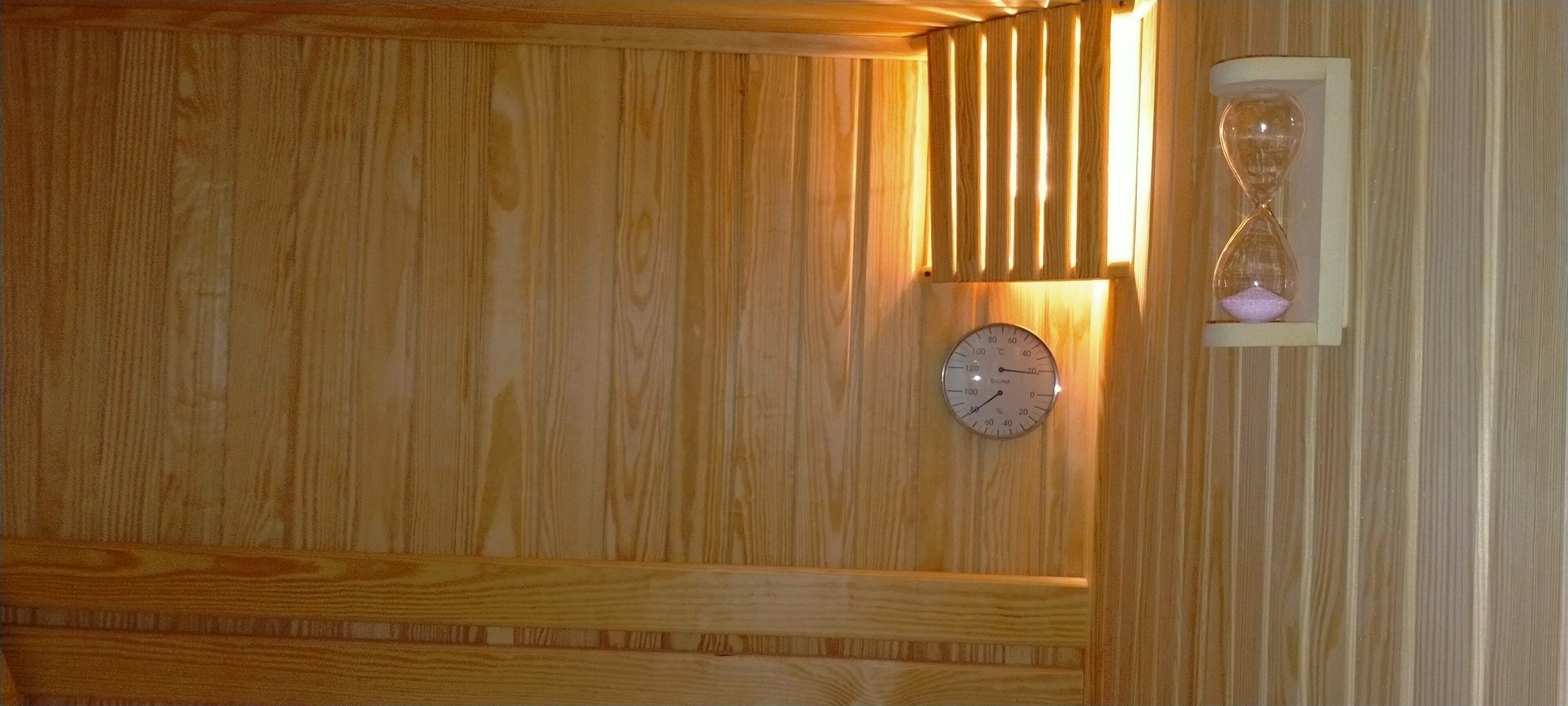Un interior de madera con una hora de arena integrada y un termómetro fijado a la pared.