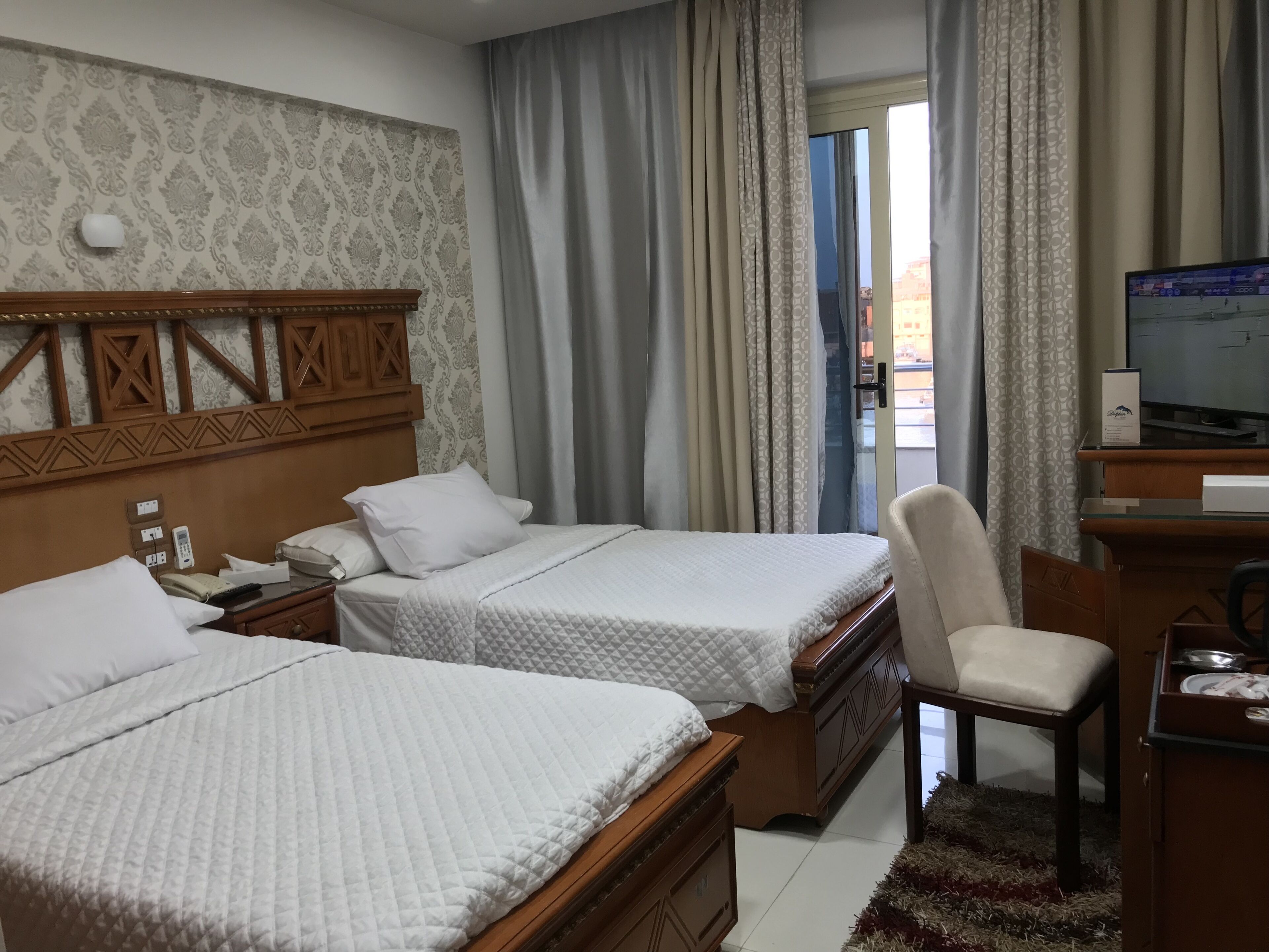 Une chambre d’hôtel avec deux lits, un bureau avec une télévision et une chaise.