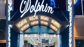 Entrada de un hotel con un letrero de neón que dice "Dolphin" y un gráfico de delfín.