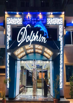 A hotel entrance with a neon sign reading "Dolphin" and a dolphin graphic.