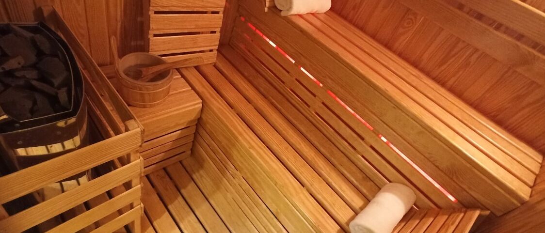 Un sauna en bois avec des bancs, une serviette et un récipient en bois.