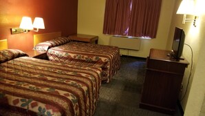 A hotel room with two beds, a desk, a TV, and a window with curtains.