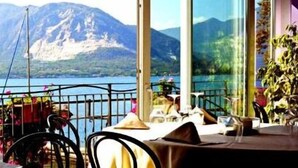 A dining area with a mountain view, large windows, and a table set for two. - Hotel Ristorante Beata Giovannina (Verbania)