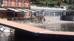A waterfront property with a dock, a building with balconies, and a restaurant with outdoor seating. - Hotel Ristorante Beata Giovannina (Verbania)