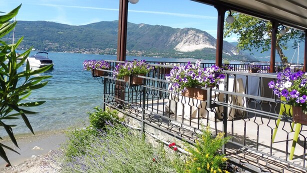 A balcony with metal railings and flower planters, overlooking a lake with boats and mountains in the background. - Hotel Ristorante Beata Giovannina (Verbania)