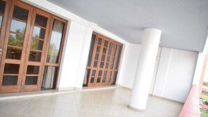 Una habitación amplia con grandes puertas de madera y suelo de baldosas.