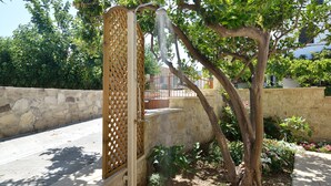 Un jardin avec un mur de pierre, une porte en bois et un arbre.