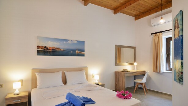 Une chambre d ’hôtel avec un lit, des tables de chevet, un bureau, une chaise, un tableau et une fenêtre avec des rideaux.