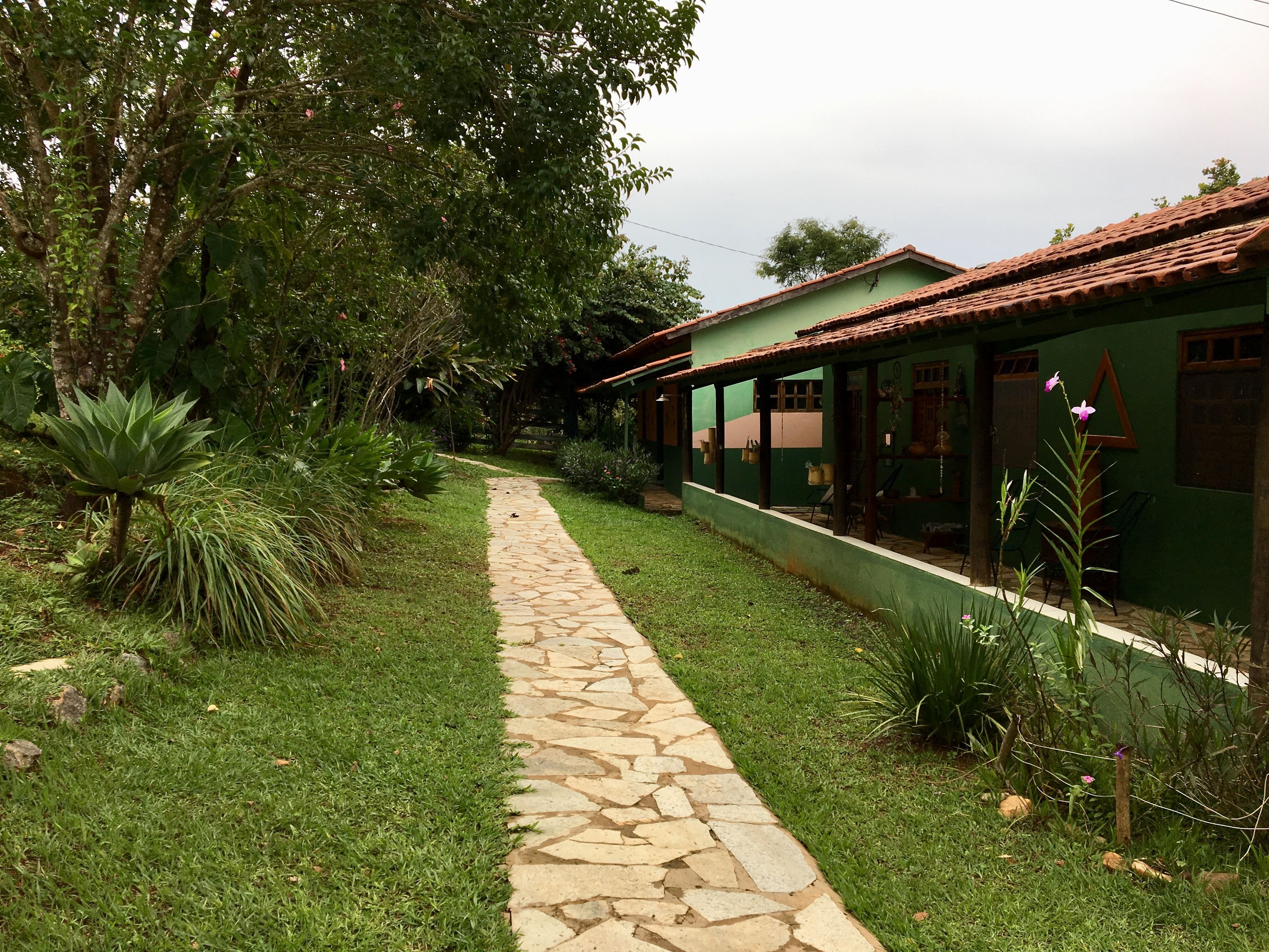 Uma trilha de pedra leva a um edifício verde com telhado de telhas.