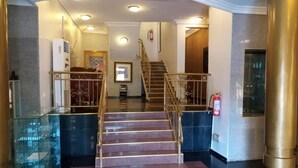 Un hall d’hôtel avec un escalier, un comptoir d’accueil et un extincteur.
