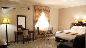 Une chambre d’hôtel équipée d’un lit, d’un bureau, d’une chaise, d’une lampe et d’une grande fenêtre avec des rideaux.