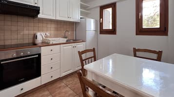 A kitchen with white cabinets, a Bosch oven, a sink, and a table with chairs.