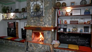 A cozy room with a stone fireplace, shelves with books and decorative items, and a chalkboard with inspirational quotes. - Poed Residences (Platres)