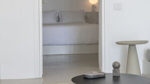 Una habitación minimalista con una cama, una mesa redonda y una mesita con una lámpara.