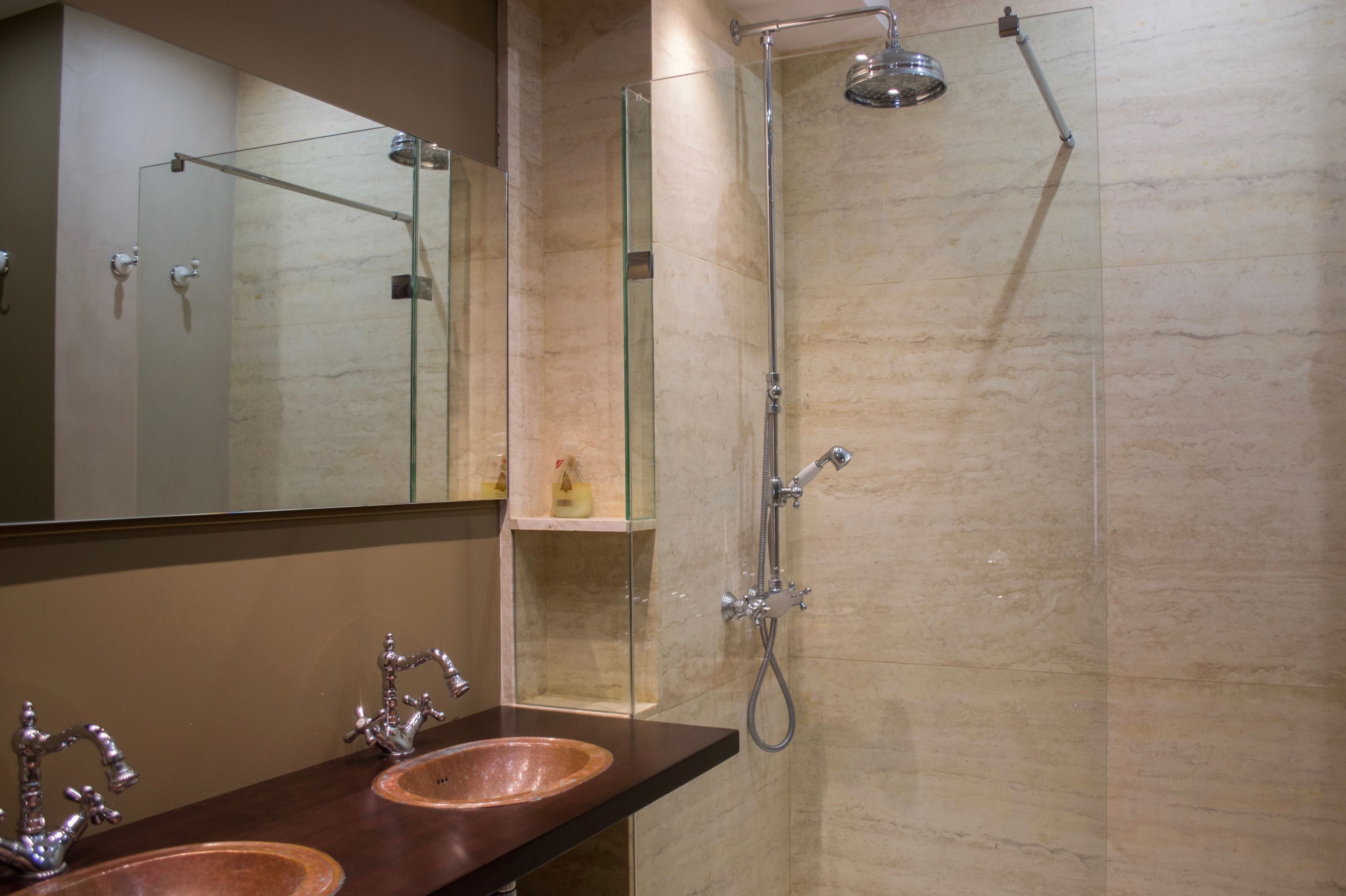 A bathroom with two sinks, a glass shower enclosure, and a mirror.