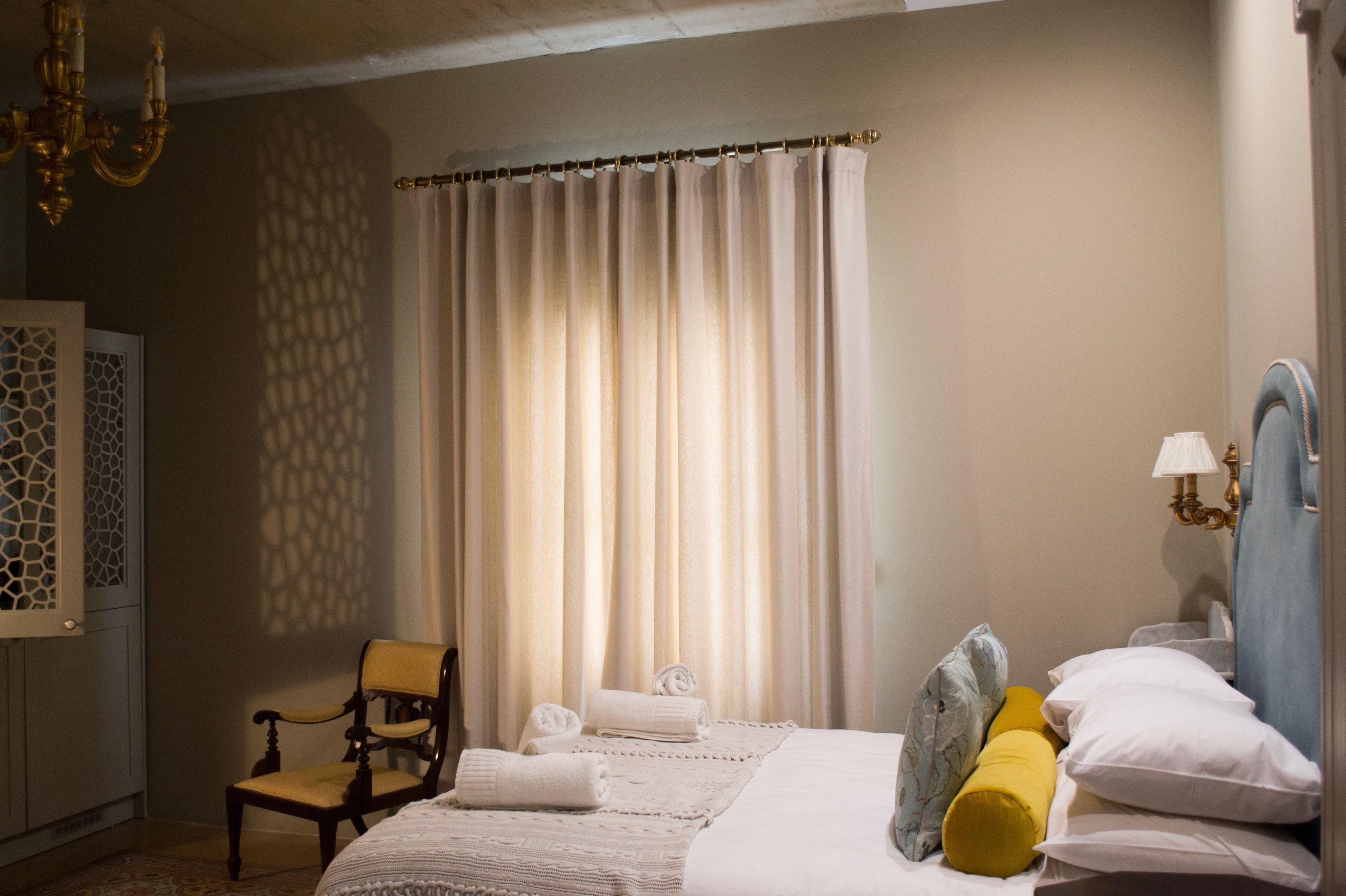 Una camera d'albergo con un letto, una sedia, un armadio e una finestra con tende.