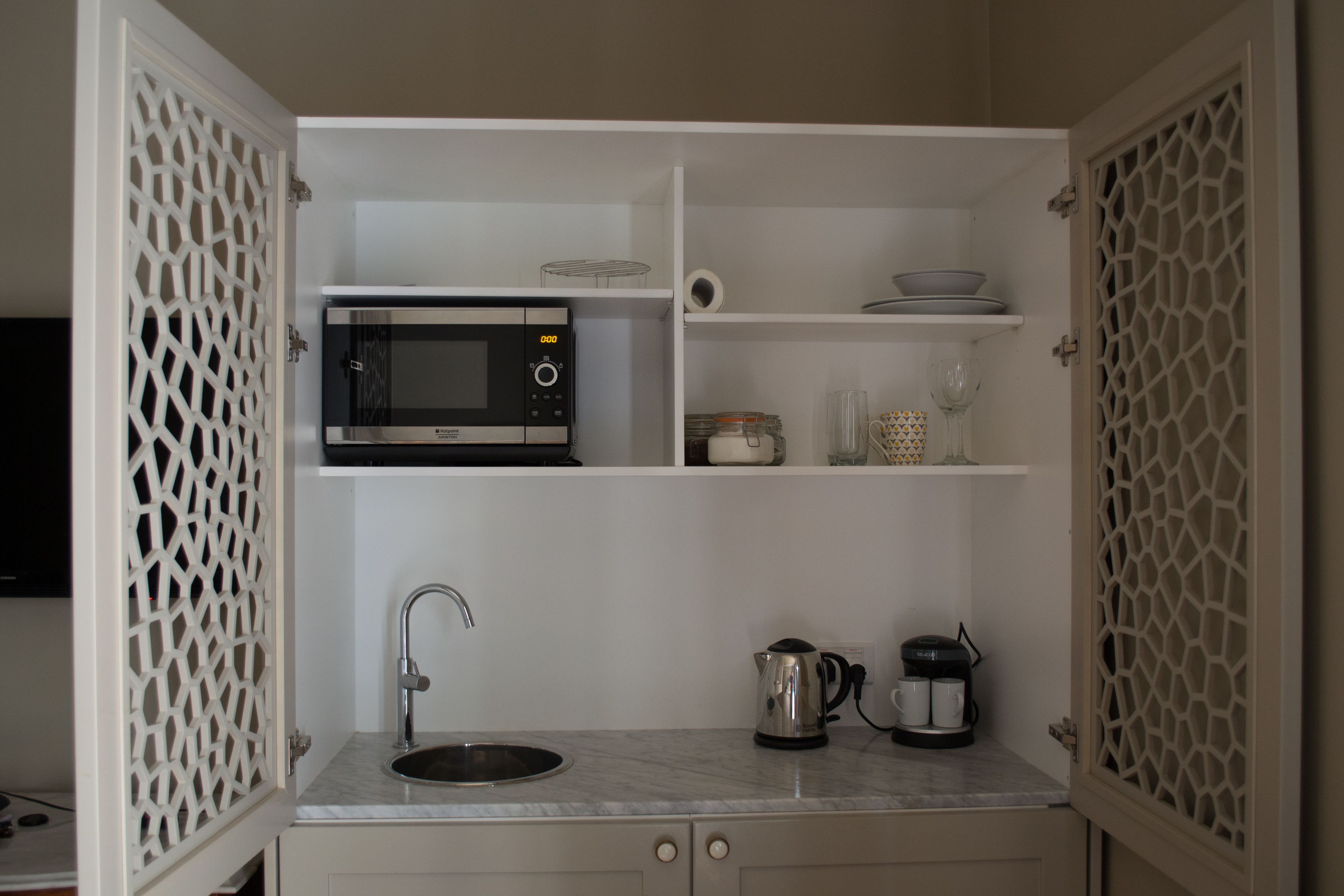 A compact kitchen with a built-in microwave, a sink, and a coffee maker.