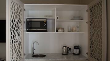 A compact kitchen with a built-in microwave, a sink, and a coffee maker.