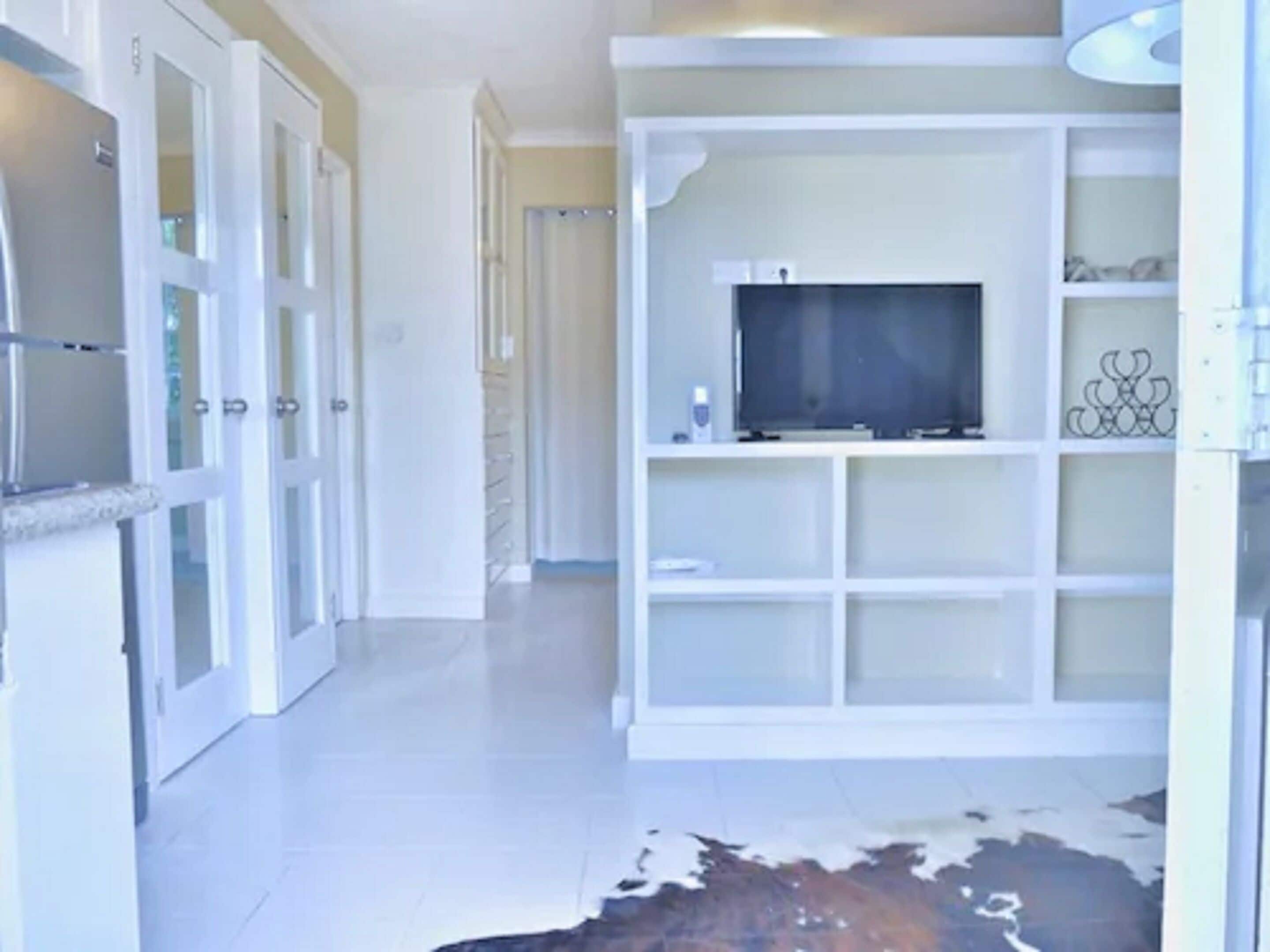 Ein Flur mit Glastür, einem weißen Schrank und einem Kuhfellteppich.