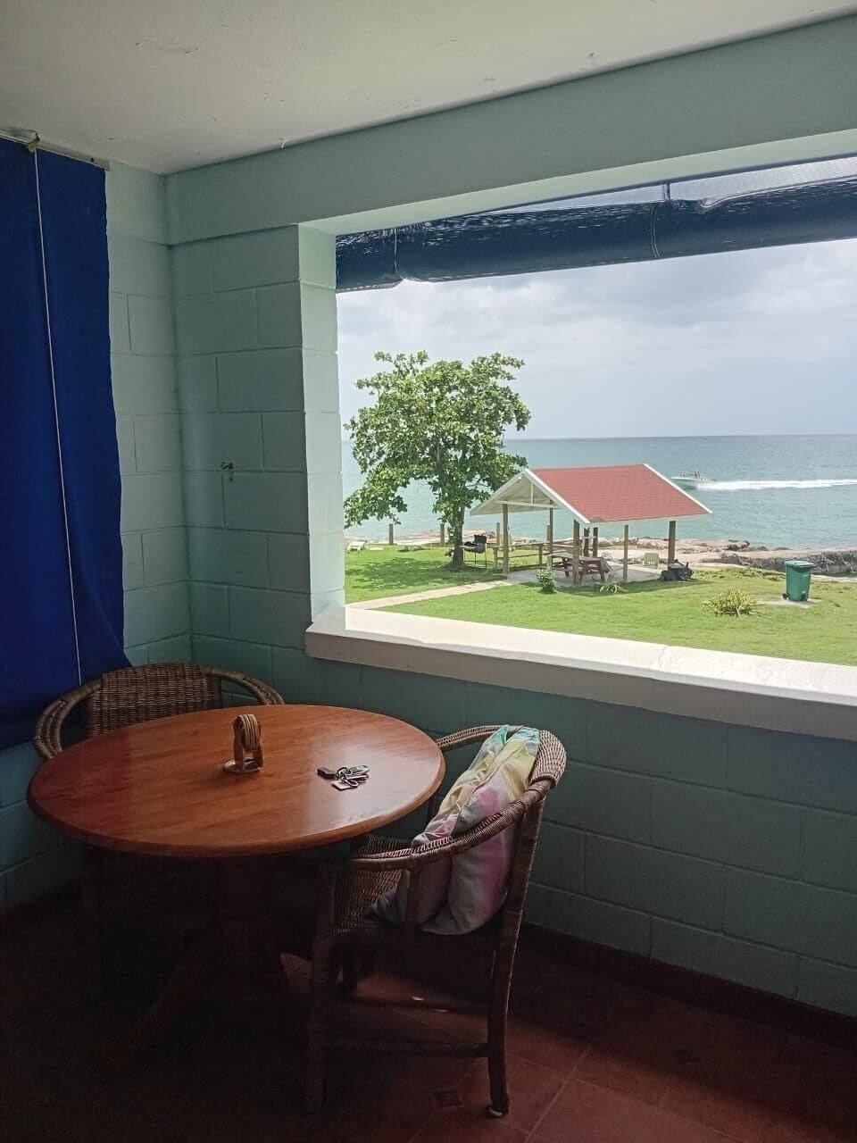 Una habitación con vista al océano, una mesa y una silla.