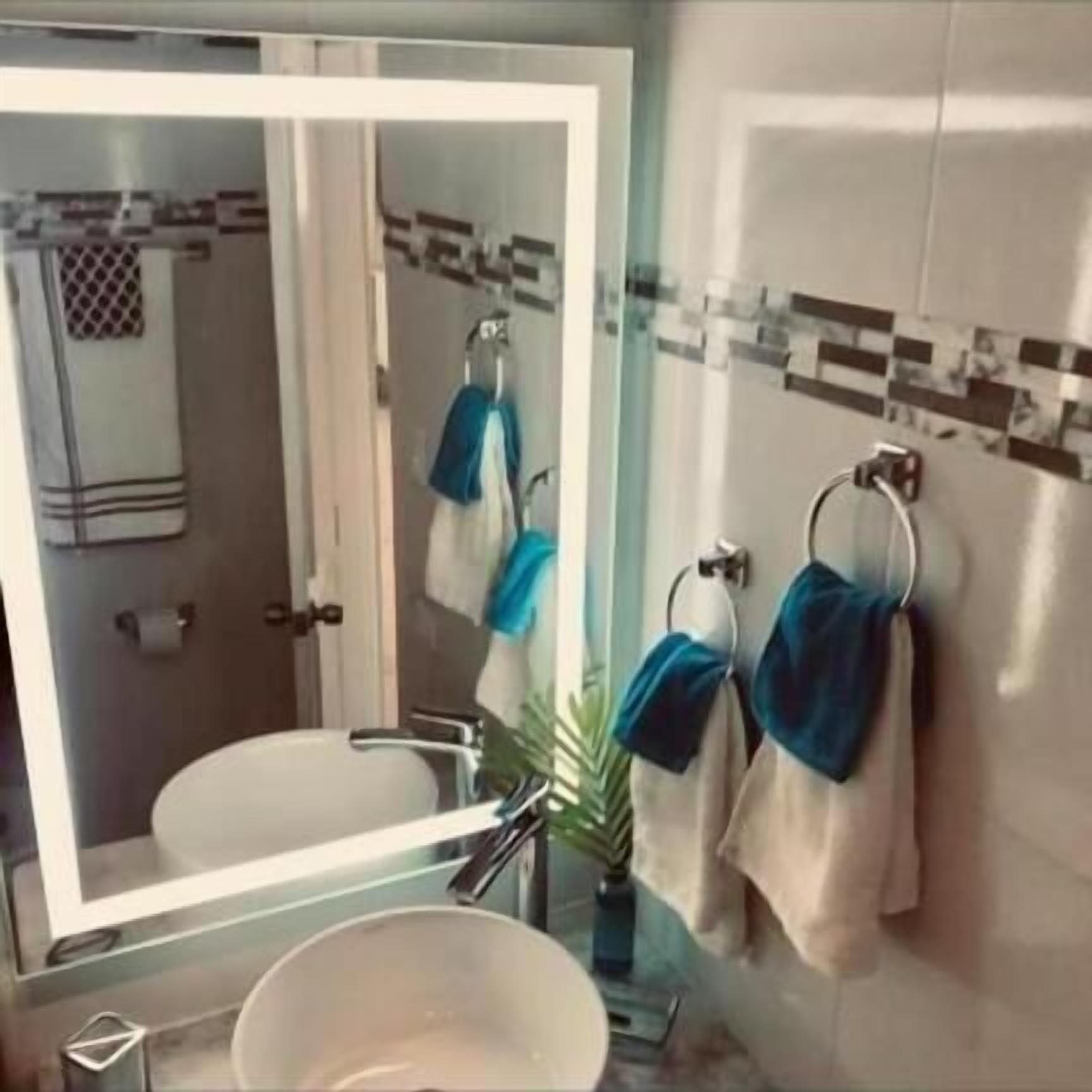A bathroom with a mirror, sink, and towel rack.