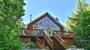 A cabin with a wooden exterior, large windows, and a balcony. - Stunning Cottage on a Very Private Lake (Kinmount)