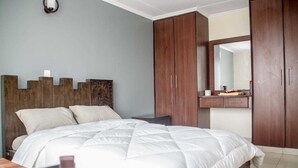 A bedroom with a bed, wooden wardrobe, and a mirror. - The Mayal Homestay (Nairobi)