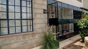 A building with large windows, a metal gate, and a number '3-04' on the wall. - The Mayal Homestay (Nairobi)