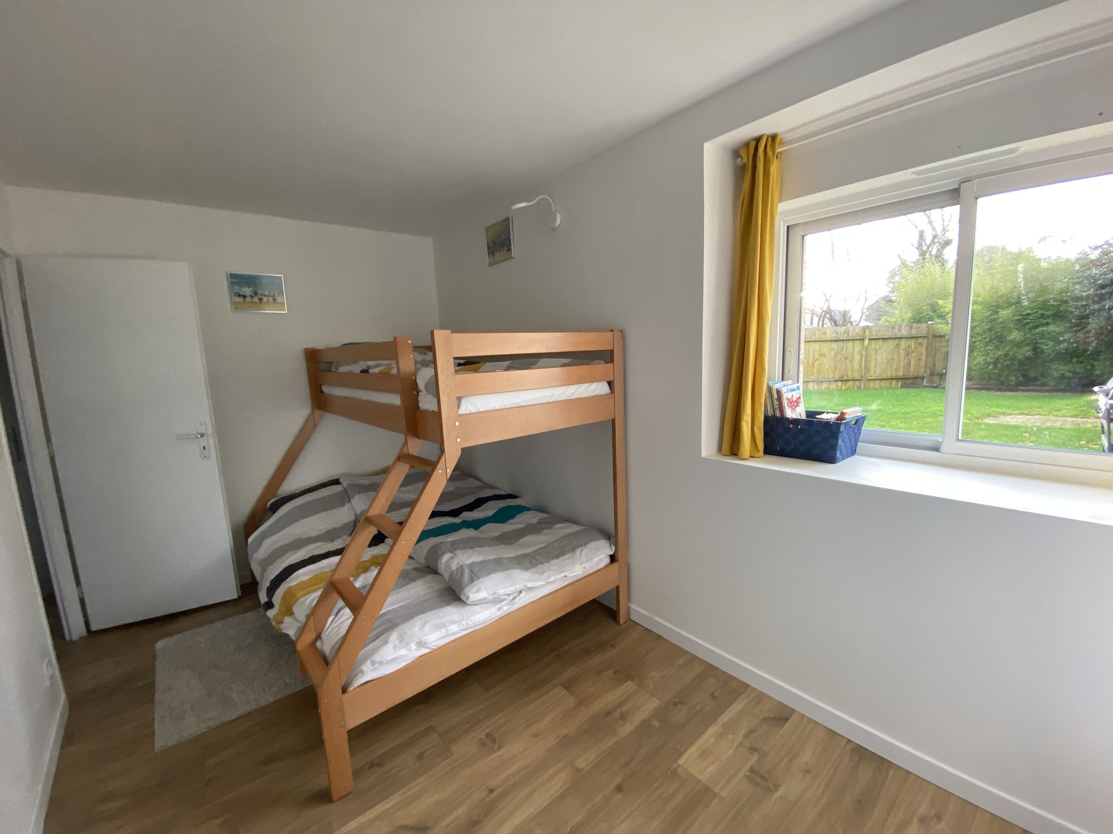 Ein Stockbett in einem Zimmer mit Fenster, Tür und einer kleinen Teppich.