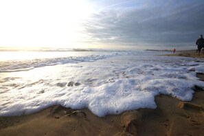 Ein Strand mit Wellen und Fußabdrücken im Sand.