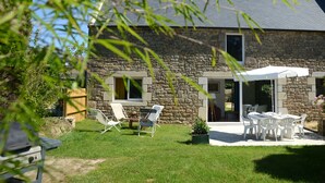 Una casa de piedra con un patio, mobiliario exterior y un pequeño jardín.