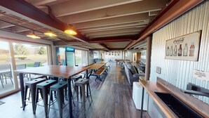 En restaurant med lange træborde og høje barstole, et køleskab til Pepsi og et Coca-Cola skilt på væggen.