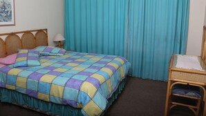 Une pièce avec un lit, une chaise, une lampe et un rideau.