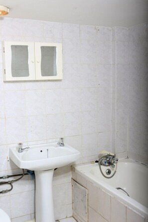 A bathroom with a pedestal sink, a bathtub, and a mirror cabinet. - Beach Mansion 3 (Margate)