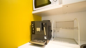 A kitchen with a coffee machine, a microwave, and a rack for hanging items. - The Sunny Reykjavik House (Reykjavik)