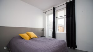 A bedroom with a bed, two pillows, a bedside lamp, and a window with curtains. - The Sunny Reykjavik House (Reykjavik)
